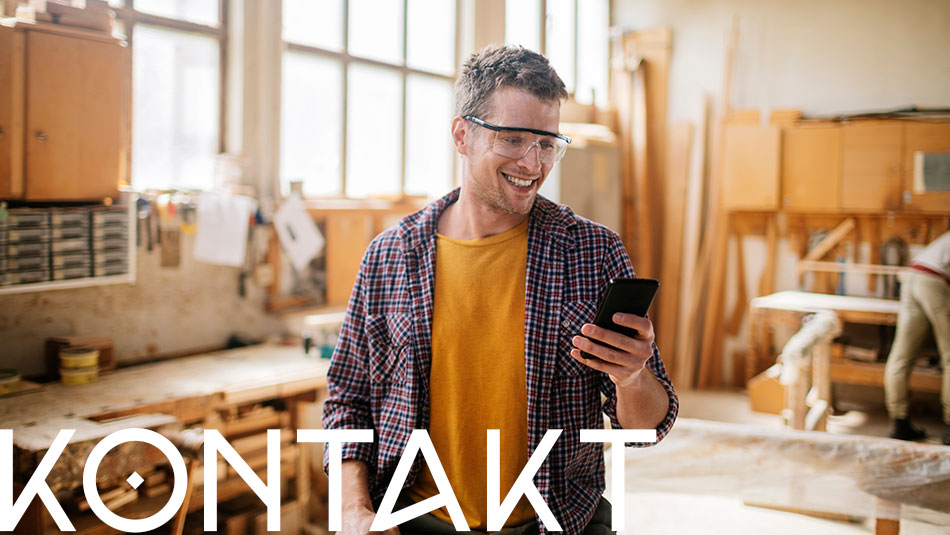 Mann in der Werkstatt mit Smartphone in der Hand