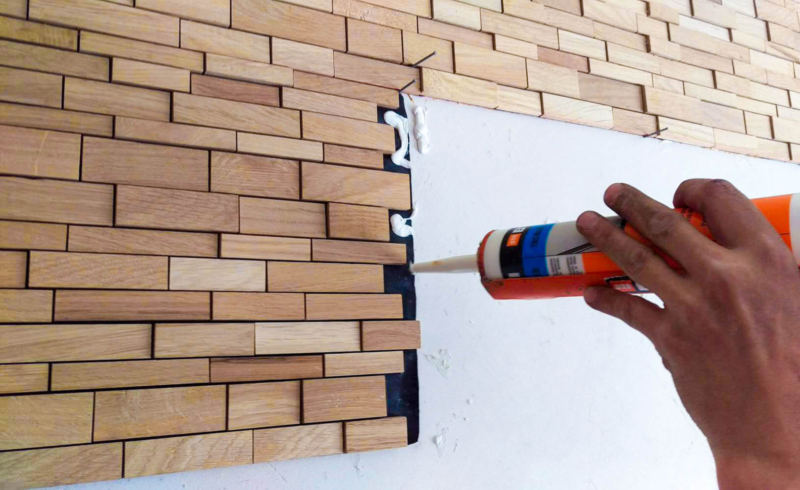 Verlegung der Holzmosaik Fliesen an einer Wand